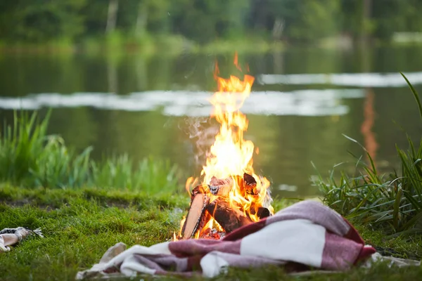 Brinnande Lägerelden Och Pläd Grönt Gräs Vid Floden Eller Sjön — Stockfoto