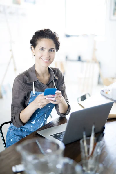 Junge Lächelnde Kreative Frau Sitzt Studio Tisch Und Schreibt Sms — Stockfoto