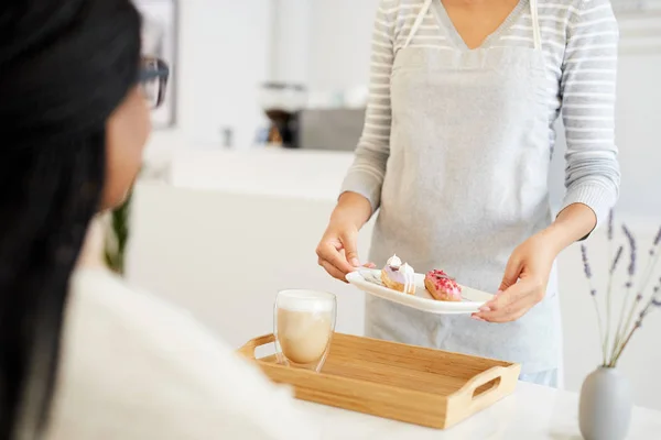 Kelnerka Płycie Przytrzymujące Dwóch Szkliwione Eclairs Dając Klienta Milkshake Drewnianej — Zdjęcie stockowe