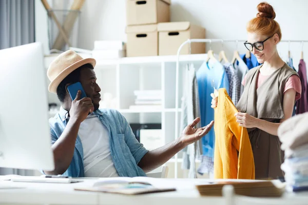 Young Fashion Designer Talking Client Smartphone While Female Colleague Helping — 스톡 사진