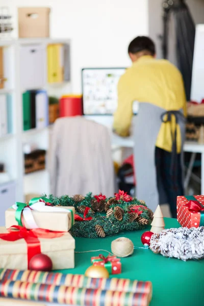 クリスマスプレゼント おもちゃや背景に取り組んでいる若い男とテーブルの上の装飾 — ストック写真