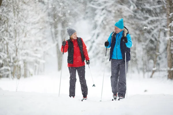 Aktives Senioren Paar Auf Skiern Fährt Bei Schneefall Schneewehe Hinunter — Stockfoto