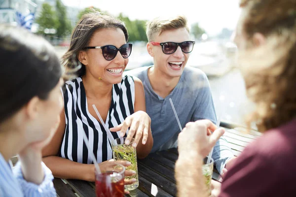 屋外カフェで飲み物でおしゃべりするサングラスやカジュアルウェアを着た若い男女の幸せ — ストック写真