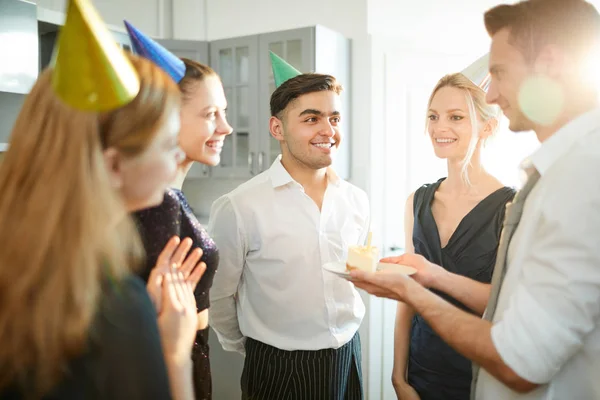 パーティーで彼の友人にろうそくを燃やすバースデーケーキでプレートを与える男の一人 — ストック写真