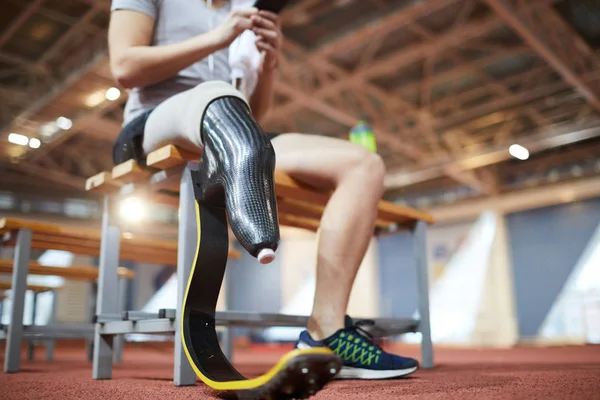 Handicapped right leg of young paralympic sportsman having break after training on stadium