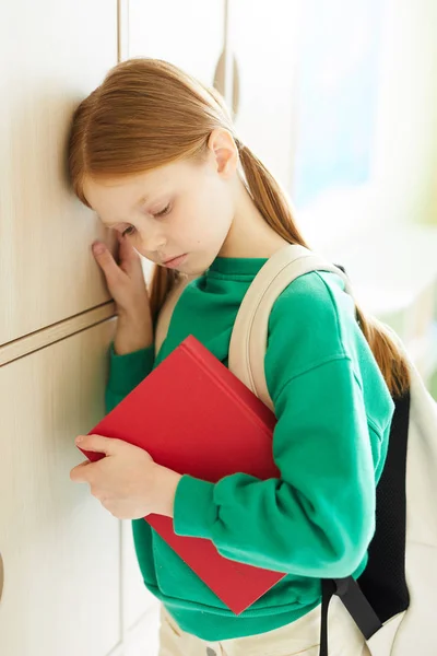 ポニーテールを持つ赤毛の女子高生は ワークブックを持って落ち込んでいて 木製のロッカーに寄りかかって 学校の概念でいじめ — ストック写真