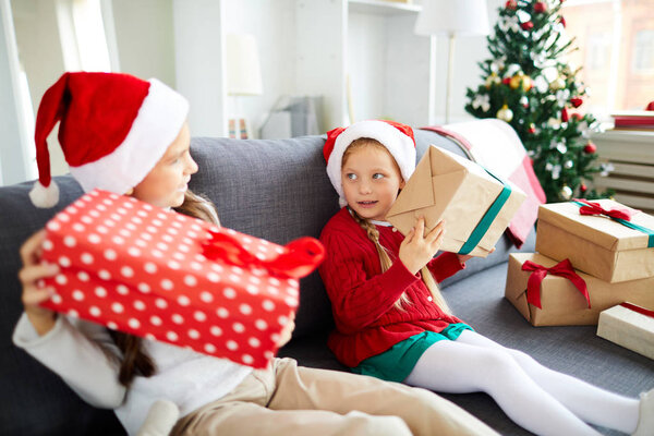 Cute Santa siblings shaking giftboxes while trying to guess what is inside