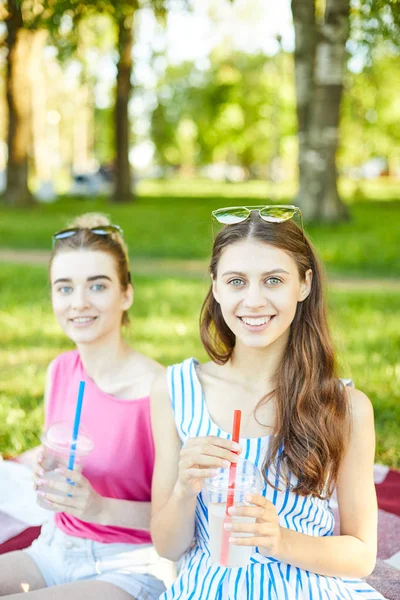 漂亮的女孩与饮料和她的朋友附近看相机在炎热的夏天闲逛 — 图库照片