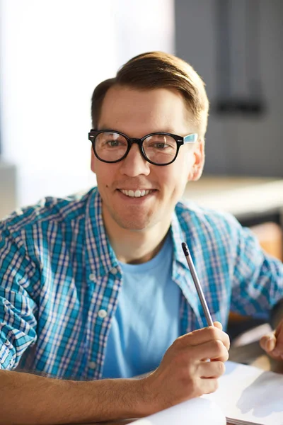 戴着眼镜和休闲衬衫的年轻商业专业人士的肖像 坐在会议桌旁听同事的合影时开心地笑了 — 图库照片