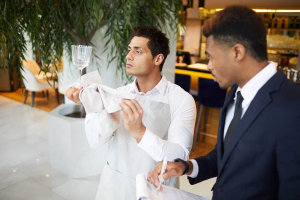 Junger Afrikanischer Restaurantbesitzer Schaut Wie Kellner Das Weinglas Putzt — Stockfoto