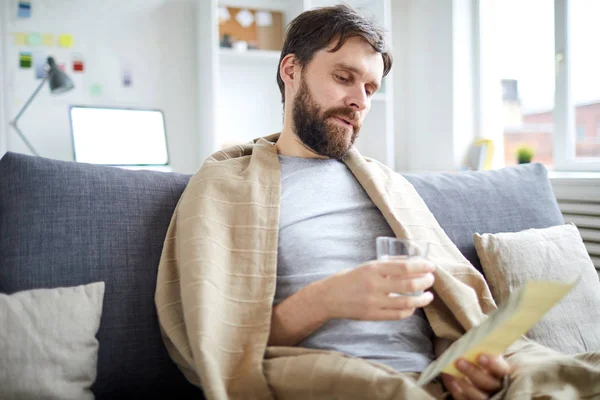 Bearded Man Met Glas Water Lezen Betalingsrekening Terwijl Zittend Bank — Stockfoto