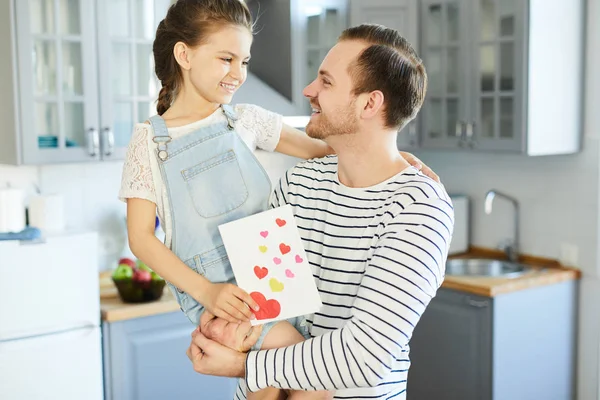 手作りのグリーティングカードを持つ陽気な小さな女の子と彼女の父親はお互いを見て — ストック写真