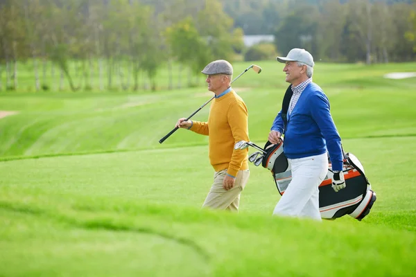 Two Senior Sportsmen Golf Clubs Walking Vast Green Field While — Stock Photo, Image