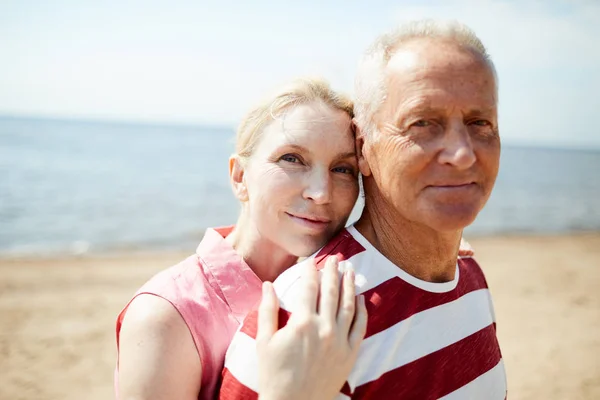 快乐和多情的成熟女人站在她的丈夫身边 而两个在海边放松 — 图库照片