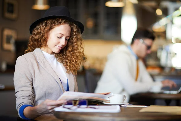Şapkalı Dalgalı Saçlı Genç Bir Kadını Kafede Otururken Gazetede Son — Stok fotoğraf