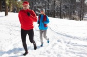 Happy zralý muž a žena v sportovní běží dolů závěje na zimní ráno