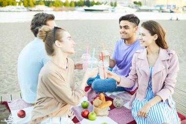 Dost çocuklar ve kızlar yaz günü plaj partisi tadını çıkarırken içecekler ile tost