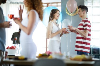 İçki içen genç çift neşeli bir atmosferde doğum günü partisinde sohbet ediyorlar.