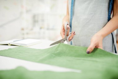 Masada santimetre ayakta ve atölyede makas ile kumaş kesme ile tanınmaz kadın terzi yakın çekim
