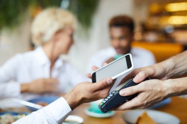 Tanınmayan işadamının online ödeme için terminale akıllı telefon koyarak yakın çekim, o restoranda öğle yemeği için ödeme
