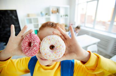 Sırt çantası ile komik kız öğrenci gözleri tarafından çörekler delikleri ile size bakıyor