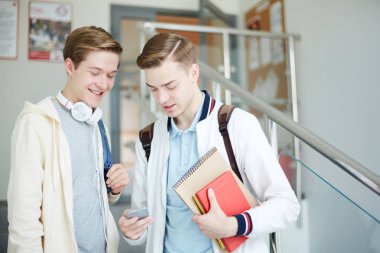 Casualwear iki dostu çocuklar merdiven üzerinde duran ve mesaj okuma veya akıllı telefonda video izlerken