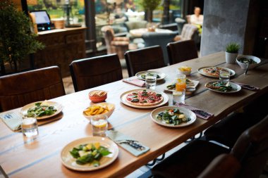 Kafedeki ahşap masa ya da restoranda misafirler için salata, pizza ve diğer atıştırmalıklarla servis edilir.