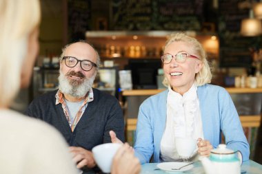 Yaşlı çift onların arkadaşı çay tarafından meraklı Haberler Cafe tartışılması sırasında konuşurken