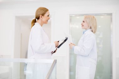 Yakında teslim edilecek yeni tıbbi ekipman hakkında konuşmak olan iş elbisesi iki kadın klinisyenler