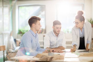 Genç kendine güvenen işkadını, mühendislere bilgi verirken belgeye işaret ediyor