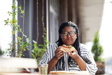 Memnun genç kadın kafede nefis pizza yemek ve onun fantastik tadı zevk