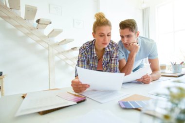 Stüdyoda çalışırken yeni trendlerin tanımı ile kağıtları okuyan ciddi gündelik tasarımcılar