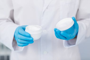 Eldivenli kozmetik yüz kremi ve kendini önünde kapağı ile plastik kavanoz tutan