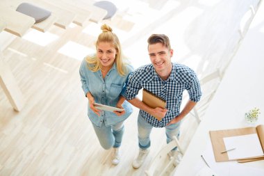 Genç tasarımcı sana bakıyor ve stüdyoda çalışırken gülümsüyor.