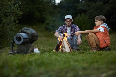 Baba ve oğlu birlikte kamp ta vakit geçiriyorlar, şekerleme pişiriyorlardı.