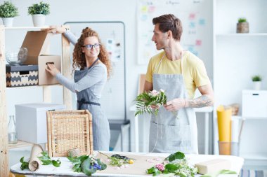 Paket hazırlarken ve çiçek demetleri yaparken stüdyolarında konuşan iki genç çiçekçi