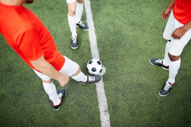Futbol topu yeşil alan üzerinde ve üç futbolcular oyun sırasında ayakta genel bakış
