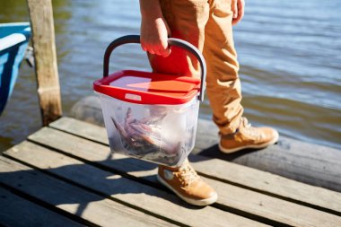 Rıhtımda dururken kova dolusu balık tutan çocuğun yakın çekimi