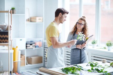 Genç bir kadın, güzel bir çiçek kompozisyonu oluşturma konusunda konuşurken meslektaşına danışıyor.