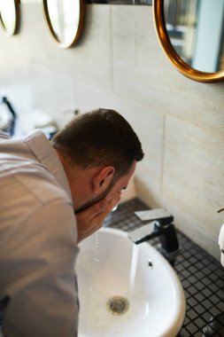 Havaalanı banyoda lavabo üzerinde serin su ile canlandırıcı yorgun veya uykulu işadamı