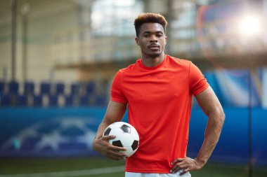 Kırmızı futbol topu Stadyumu'nda ile Tekdüzen ayakta Afrikalı-Amerikalı genç adam