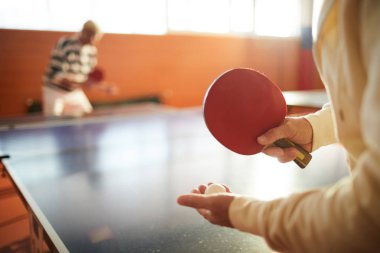 Karşı tarafta başka bir adam ile büyük masa ayakta iken olgun tenis oyuncusu tutarak ekipmanları
