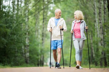 Yaz haftasında yeşil ağaçlar arasında parkta trekking pratik Senior aktif çift
