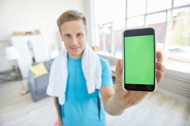 Akıllı telefonun dokunmatik ekranında meraklı pic veya promo gösteren aktif genç adam