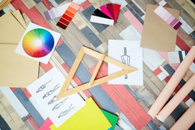 Tasarımcının yaratıcı alanı: üçgen cetvel, renk ve moda skeçleri ile renkli masanın yüksek açı görünümü