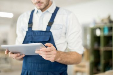 Yeni teknik proje için fikir ararken iş kıyafetleri bölümünde çalışan genç bir adam touchpad tutuyor.