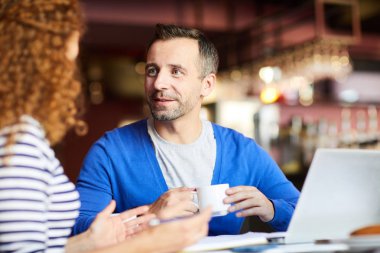 Kafede gayri resmi toplantı sırasında sakal kahve içme ve kadın bakarak İçerik yakışıklı işadamı