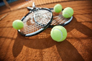Bir tenis topu birkaç daha fazla ve iki arka plan üzerinde kumlu sahada raketleri