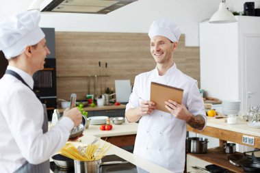 Sınıfta stajyer aşçı test ederken sketchpad notları yapma kol dövme ile Pozitif memnun yakışıklı genç şef