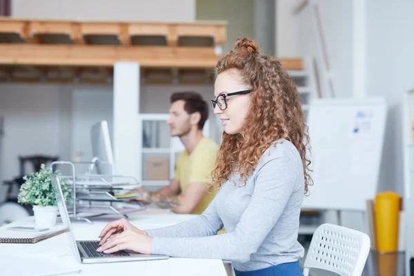 办公室或工作室中坐在笔记本电脑前的年轻女性网页设计师或程序员 — 图库照片
